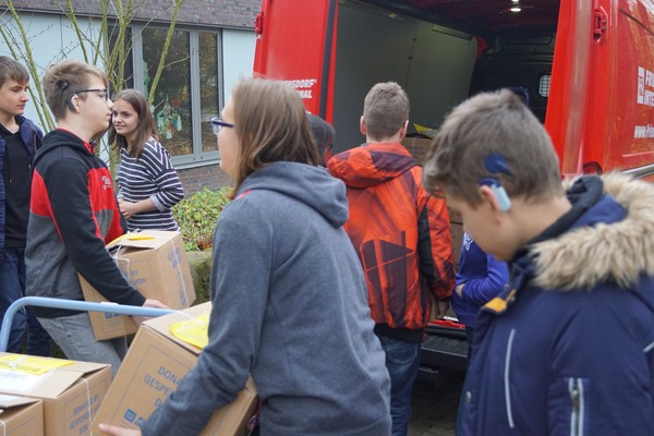 Kinder laden Pakete in den Wagen des Internationalen Friedensdorfes